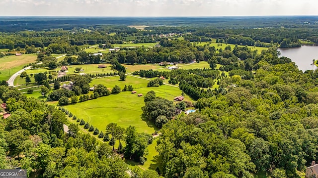 drone / aerial view with golf course view, a water view, and a view of trees