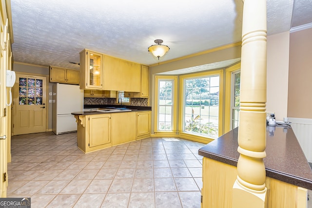 kitchen with white refrigerator, kitchen peninsula, light tile patterned floors, and decorative backsplash