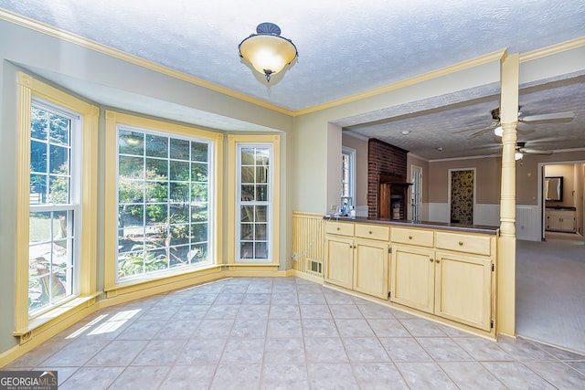 kitchen with ceiling fan, light tile patterned floors, brick wall, and crown molding