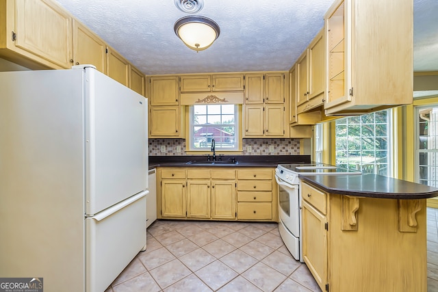 kitchen with kitchen peninsula, light tile patterned floors, backsplash, white appliances, and sink