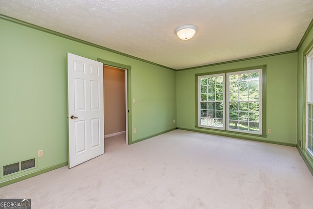 unfurnished bedroom with light carpet, a textured ceiling, and ornamental molding