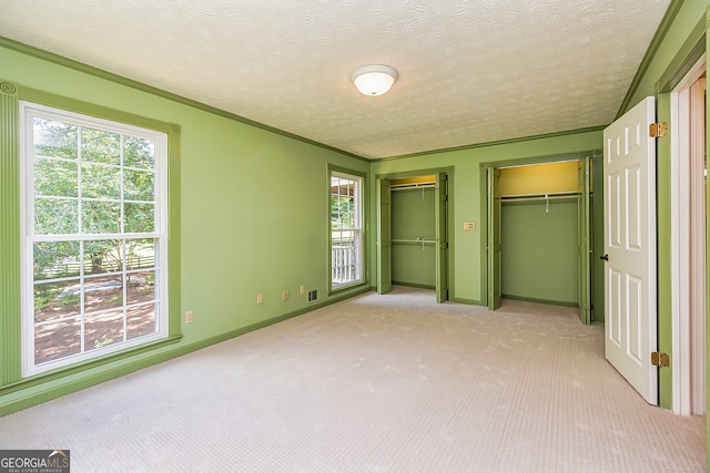 unfurnished bedroom featuring light carpet, a textured ceiling, and multiple windows