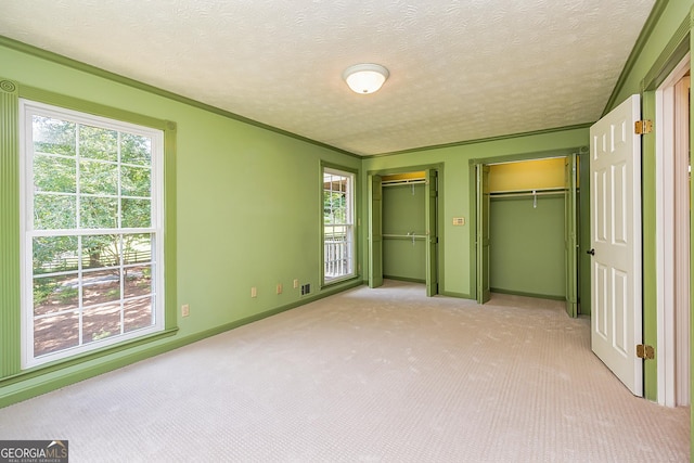 unfurnished bedroom featuring light carpet, multiple windows, and multiple closets