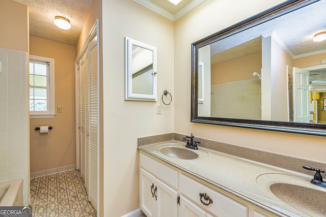 bathroom with a textured ceiling, dual vanity, and ornamental molding