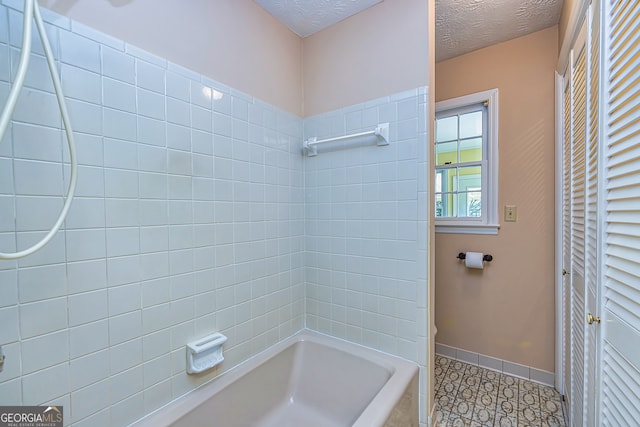 bathroom featuring tiled shower / bath combo, a textured ceiling, and tile patterned flooring