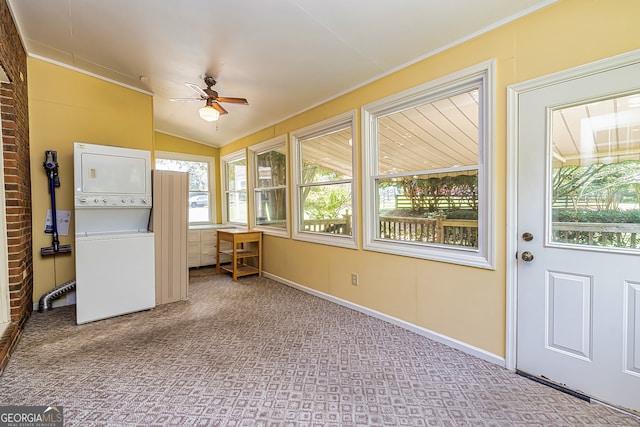 unfurnished sunroom featuring stacked washer and dryer, plenty of natural light, and ceiling fan