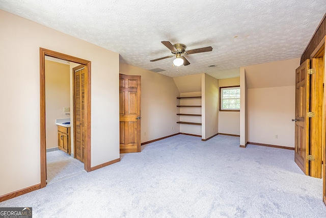 unfurnished bedroom featuring light carpet, visible vents, baseboards, lofted ceiling, and a textured ceiling