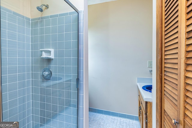 full bathroom with baseboards, tiled shower, a closet, and vanity