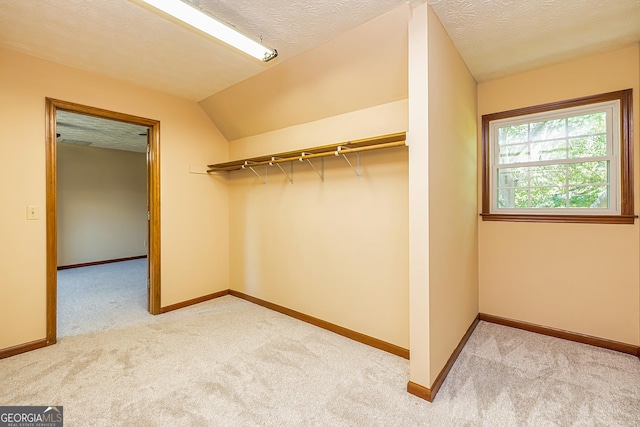 spacious closet featuring lofted ceiling and light colored carpet