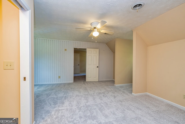 bonus room featuring ceiling fan, a textured ceiling, lofted ceiling, and light carpet