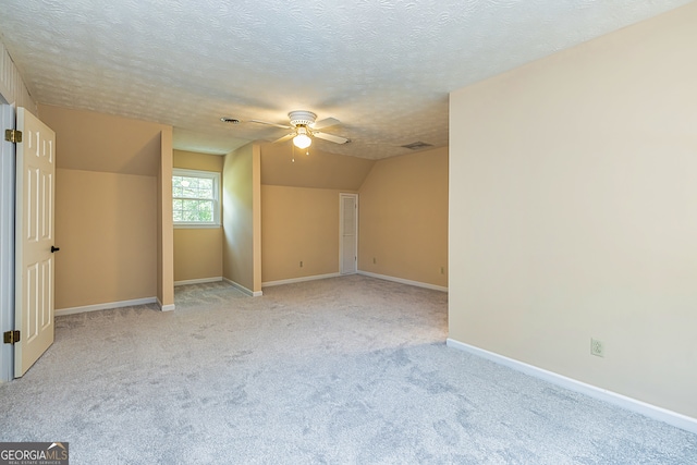 interior space featuring ceiling fan, a textured ceiling, lofted ceiling, and light carpet