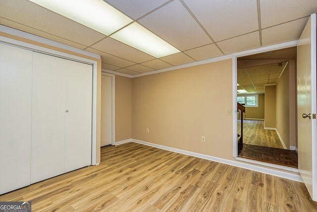 unfurnished bedroom with light hardwood / wood-style flooring, a paneled ceiling, and a closet