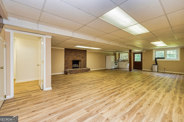 interior space featuring a brick fireplace, light hardwood / wood-style flooring, and a paneled ceiling