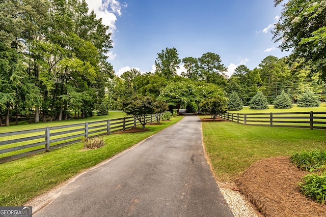 view of property's community featuring a yard, a rural view, and fence