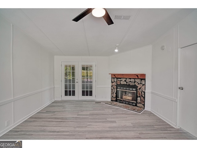 unfurnished living room with a fireplace, light hardwood / wood-style floors, vaulted ceiling, and french doors