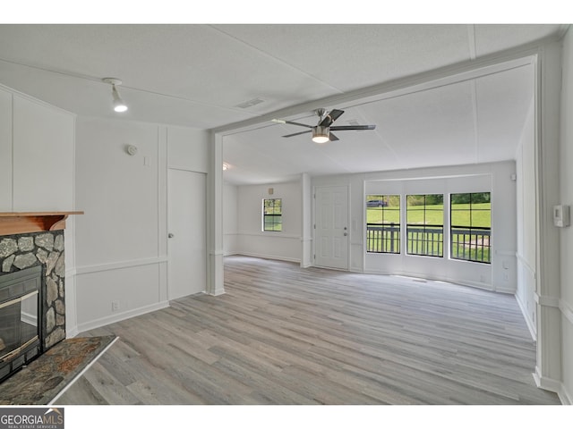 unfurnished living room featuring a stone fireplace, light hardwood / wood-style floors, and ceiling fan