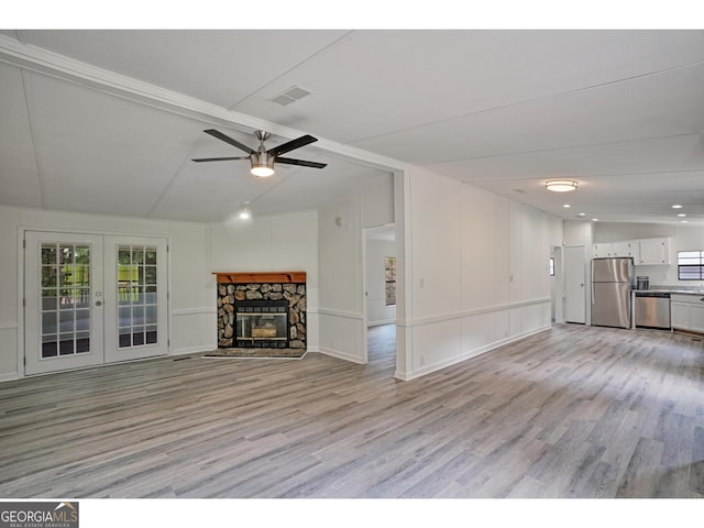 unfurnished living room featuring a fireplace, ceiling fan, french doors, vaulted ceiling, and light hardwood / wood-style floors