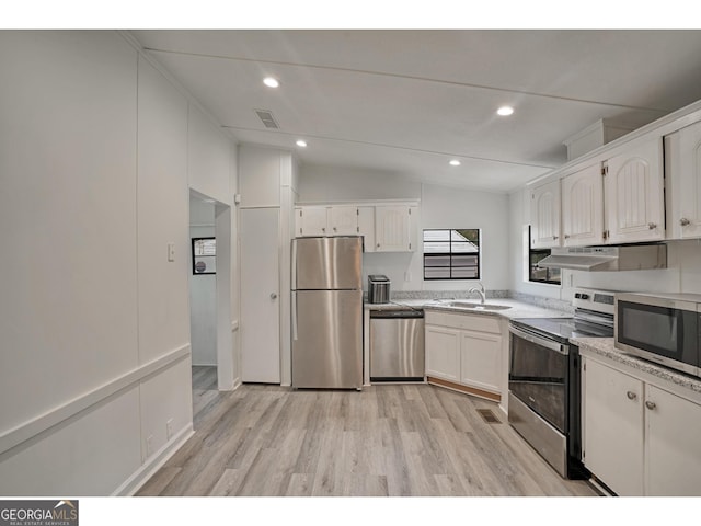 kitchen with appliances with stainless steel finishes, white cabinets, vaulted ceiling, sink, and light hardwood / wood-style floors