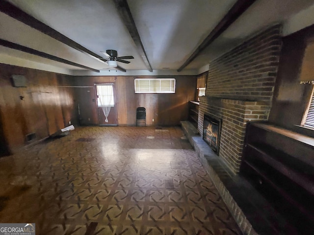 8347 Hilltop Rd, Jonesboro, GA 30236 - unfurnished living room featuring beamed ceiling, ceiling fan, a fireplace, and wooden walls