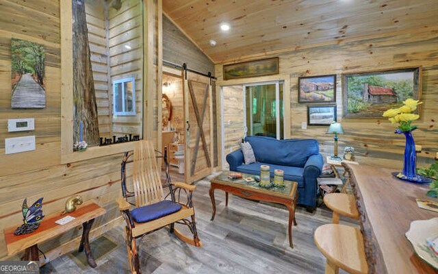 living room featuring wood-type flooring, wooden walls, and a barn door