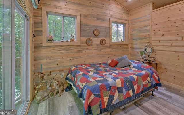 bedroom with hardwood / wood-style flooring, vaulted ceiling, and wooden walls