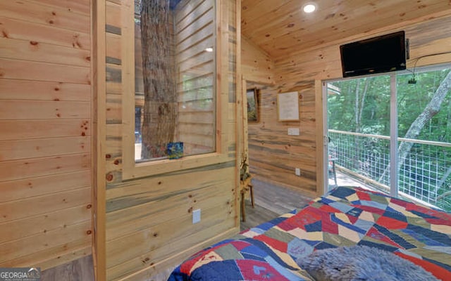 bedroom featuring wooden walls and lofted ceiling