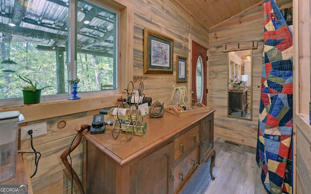 office space with vaulted ceiling, wooden ceiling, wooden walls, and light hardwood / wood-style flooring