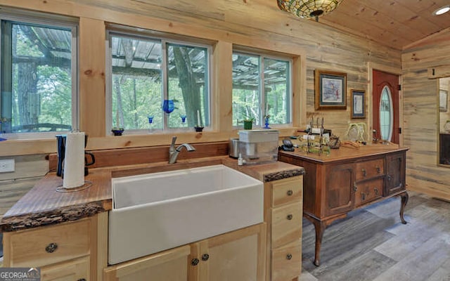 kitchen featuring wooden walls, sink, light hardwood / wood-style flooring, lofted ceiling, and wood ceiling