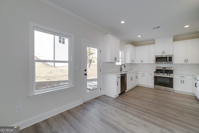 kitchen with white cabinets, light wood-type flooring, appliances with stainless steel finishes, and sink