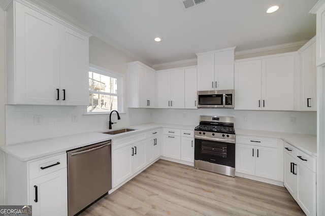 kitchen with appliances with stainless steel finishes, white cabinetry, tasteful backsplash, and sink