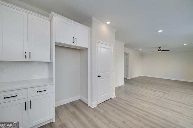 kitchen with light hardwood / wood-style floors, white cabinetry, ornamental molding, and tasteful backsplash