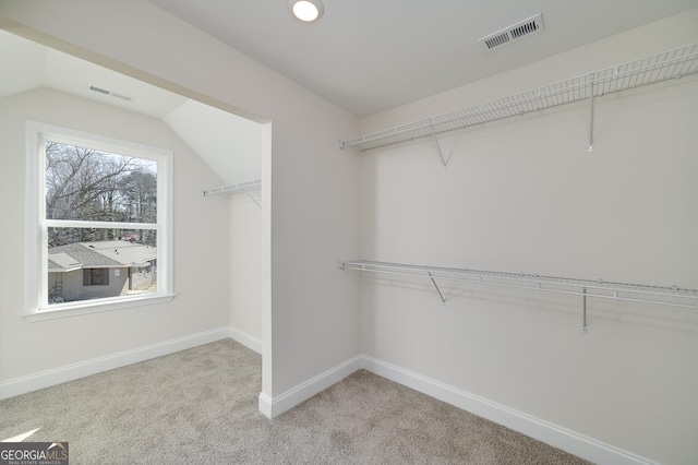 spacious closet with light carpet and vaulted ceiling