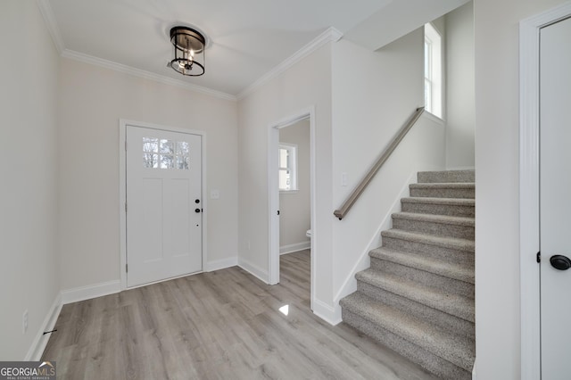 entryway featuring plenty of natural light, crown molding, and light wood-type flooring