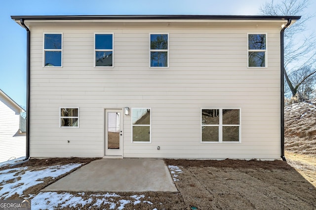 snow covered rear of property with a patio area