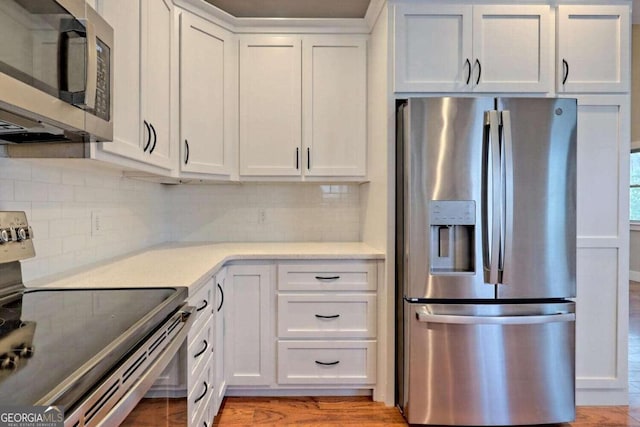 kitchen with white cabinetry, appliances with stainless steel finishes, light hardwood / wood-style flooring, and tasteful backsplash