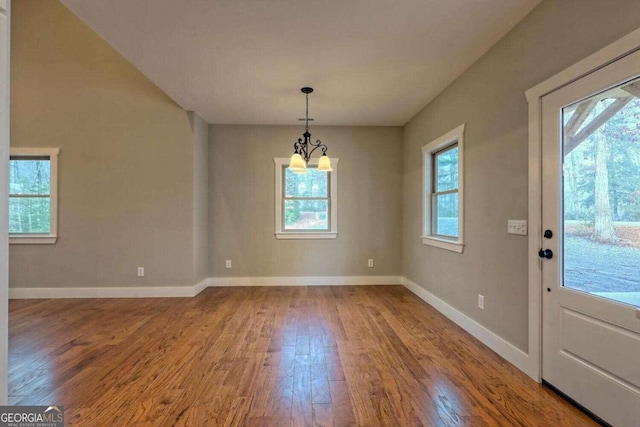 unfurnished dining area featuring hardwood / wood-style floors and an inviting chandelier