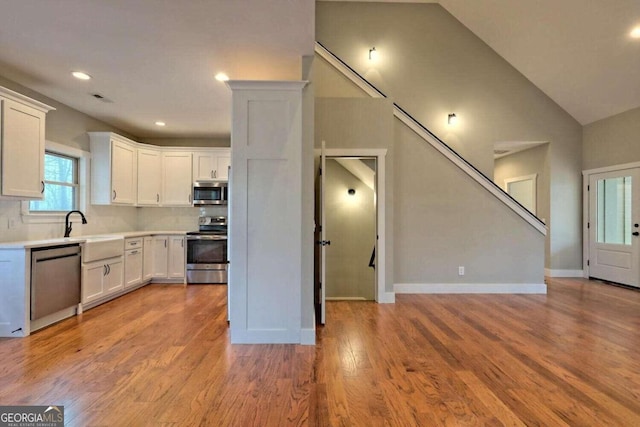 kitchen with sink, white cabinets, tasteful backsplash, and stainless steel appliances