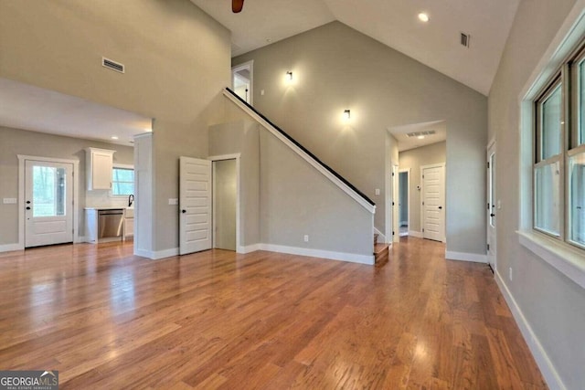 unfurnished living room featuring high vaulted ceiling and wood-type flooring