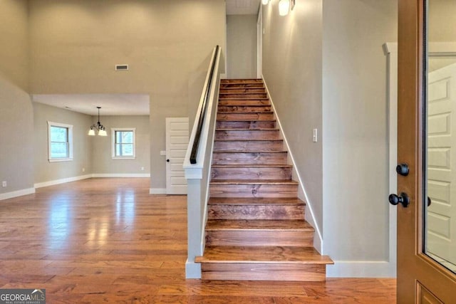 staircase featuring hardwood / wood-style floors and an inviting chandelier