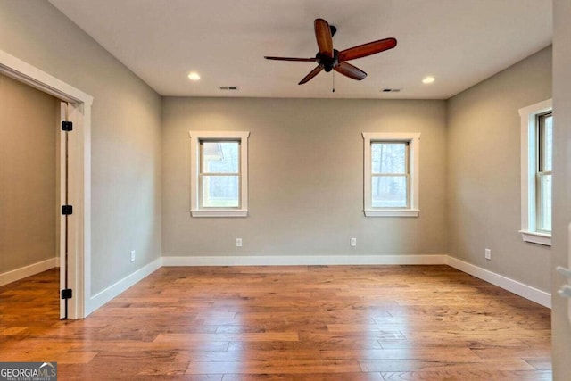 unfurnished room with ceiling fan, a wealth of natural light, and hardwood / wood-style floors