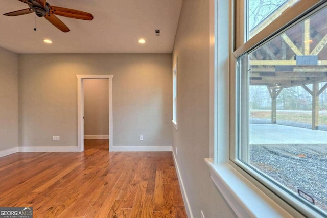 empty room featuring ceiling fan, plenty of natural light, and light hardwood / wood-style flooring