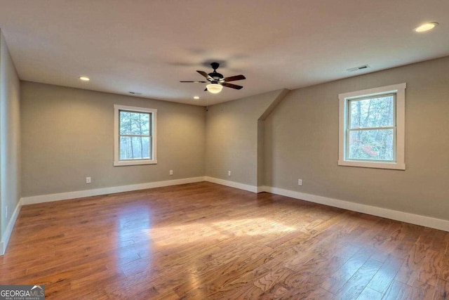 empty room featuring ceiling fan, hardwood / wood-style floors, and a wealth of natural light