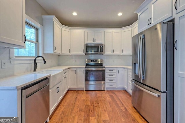 kitchen featuring backsplash, white cabinetry, sink, and stainless steel appliances