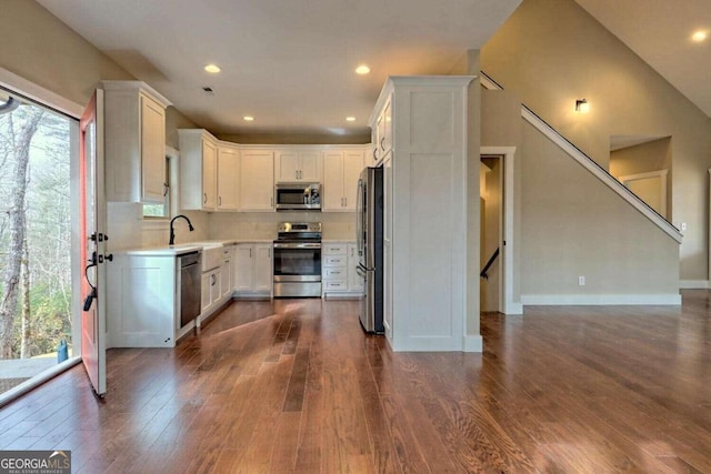 kitchen with appliances with stainless steel finishes, dark hardwood / wood-style flooring, white cabinets, and backsplash