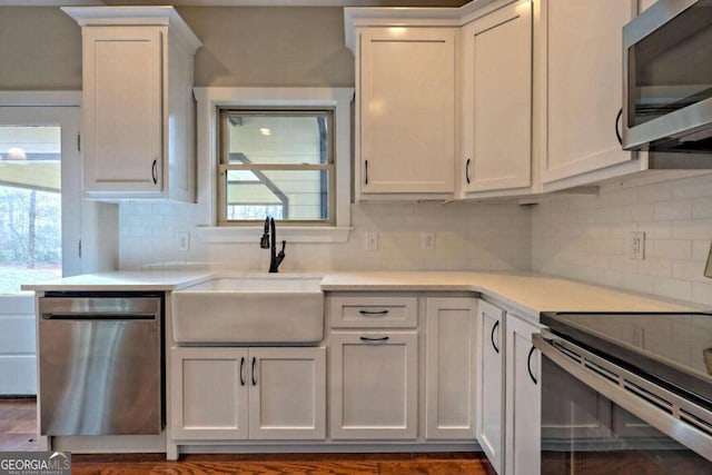 kitchen featuring appliances with stainless steel finishes, sink, decorative backsplash, white cabinetry, and dark hardwood / wood-style flooring