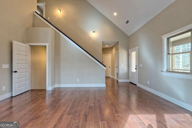 unfurnished living room featuring wood-type flooring and high vaulted ceiling