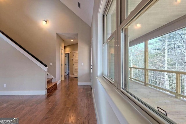 hallway with dark hardwood / wood-style floors and a high ceiling