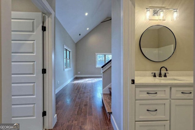 bathroom featuring hardwood / wood-style flooring, vaulted ceiling, and vanity