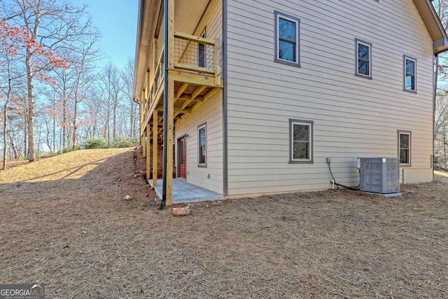 view of side of property featuring central AC, a balcony, and a patio area