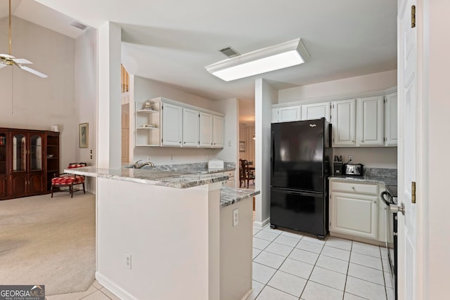 kitchen with kitchen peninsula, black appliances, light colored carpet, white cabinets, and light stone counters